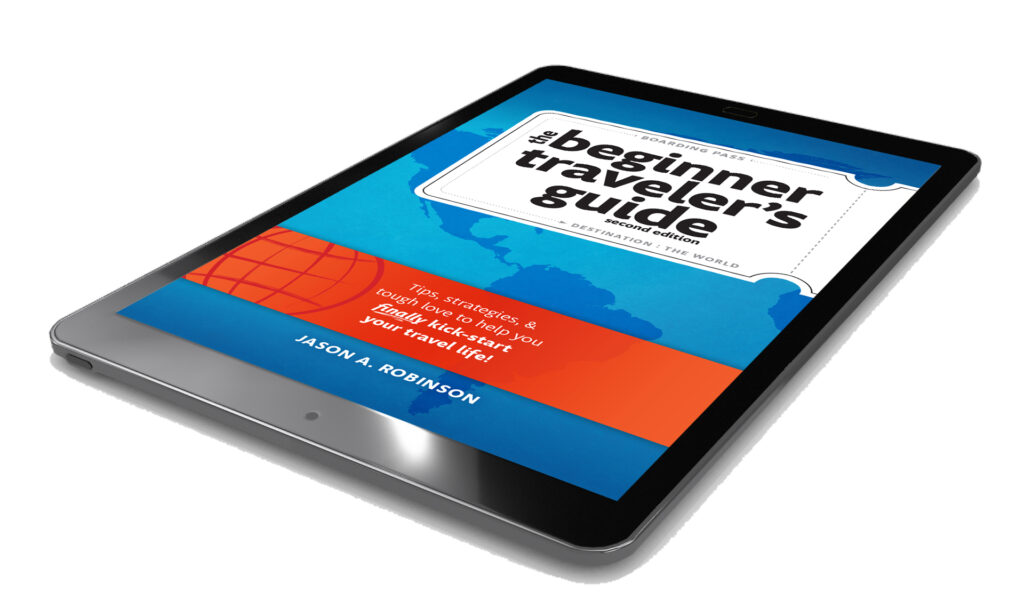 A tablet displaying the cover of the Beginner Traveler's Guide by Jason A. Robinson, featuring a blue world map background and an orange globe graphic—a must-have nomad book for every Beginner Traveler.