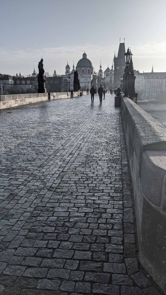 Vertical photo of a morning walk on Charles Bridge in Prague