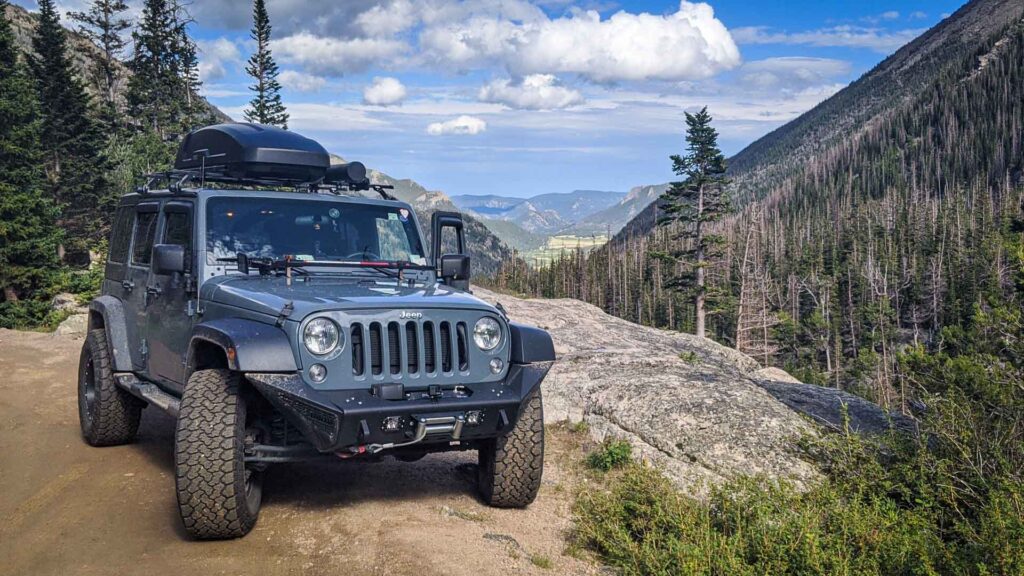 Front of Jeep Wrangler with aftermarket Addictive Desert Design Stealth bumpers on mountain road