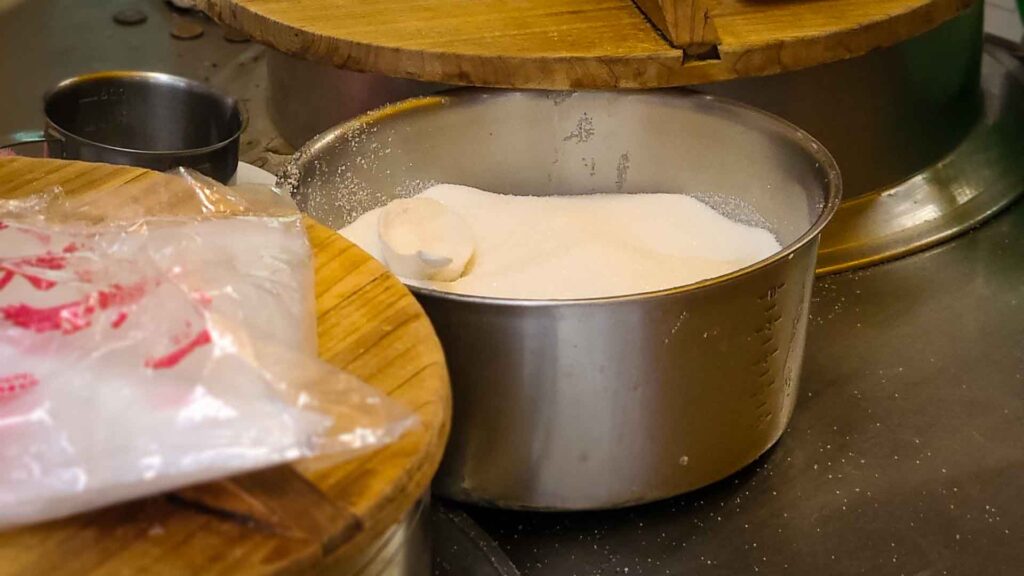 Bowl of white granulated sugar on a night market counter for adding to asian food