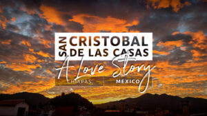 Sunset sky with vibrant orange clouds over the silhouette of San Cristobal de las Casas, Chiapas, Mexico—discover things to do in San Cristobal as “San Cristobal de las Casas: A Love Story” is overlaid on the image.